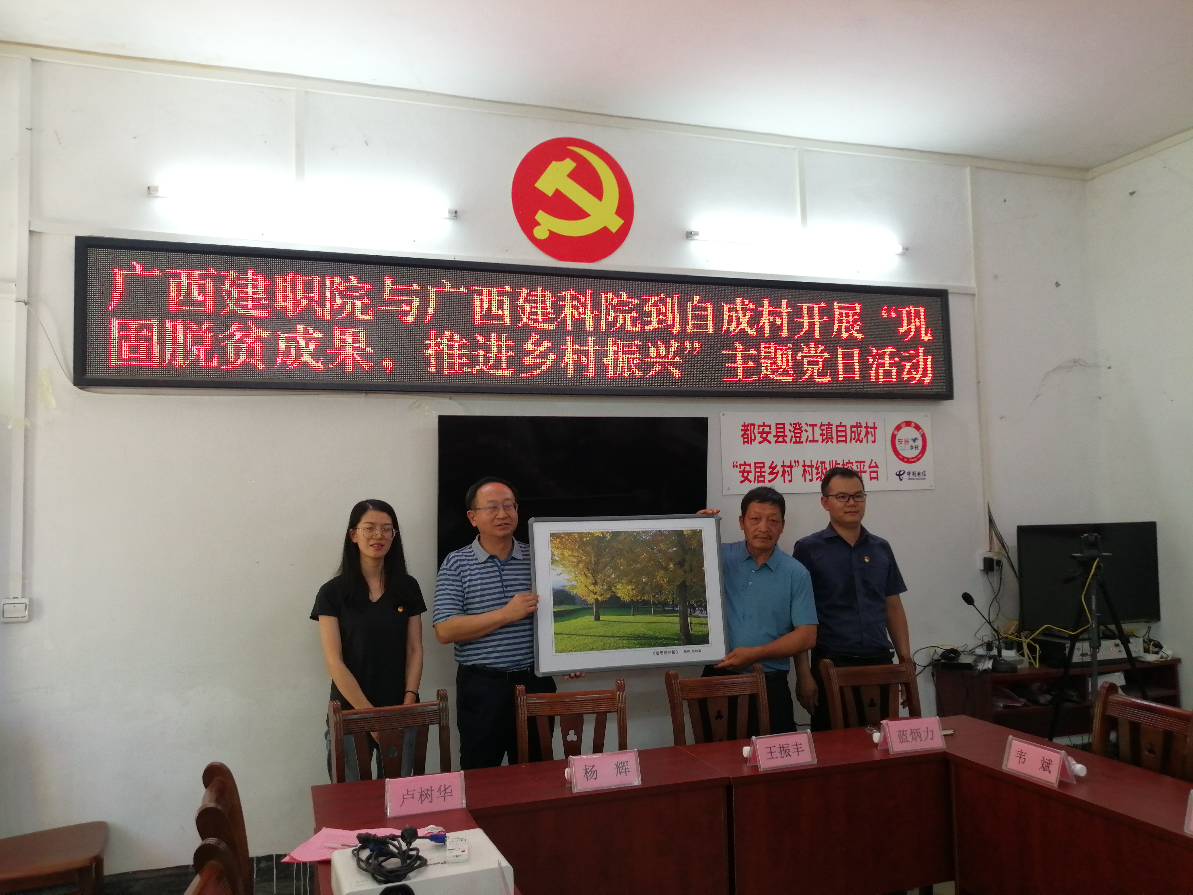 直屬公共基礎部黨支部黨員代表為村委贈送學院副院長伍耿清的攝影作品《常思晚秋醉》