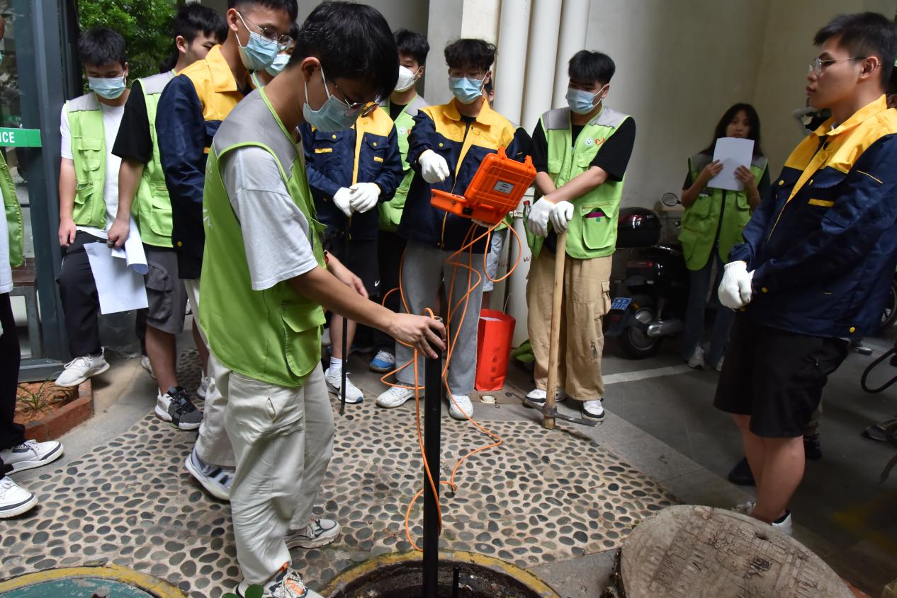 志愿者運用潛望鏡對小區(qū)排水管道進行檢測