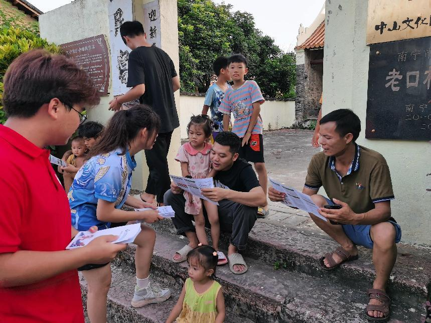 實(shí)踐團(tuán)成員在宗祠前發(fā)放宣傳手冊(cè)講解龍獅運(yùn)動(dòng)