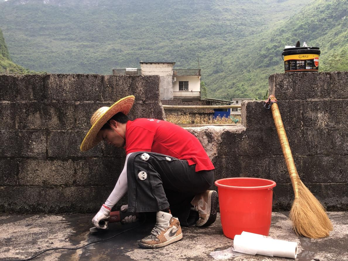 實踐團成員正在對村民屋頂裂縫處進行清理打磨